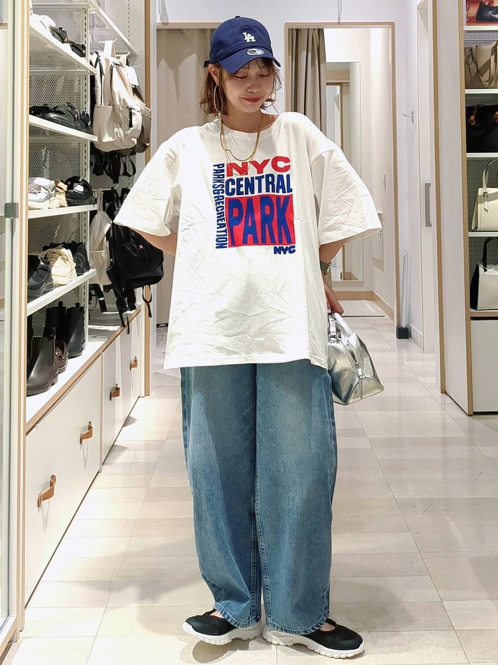 ブラック系のスニーカー、シルバー系のショルダーバッグ、ブルー系のデニムパンツを着用したレディースの春コーディネートの3枚目の写真