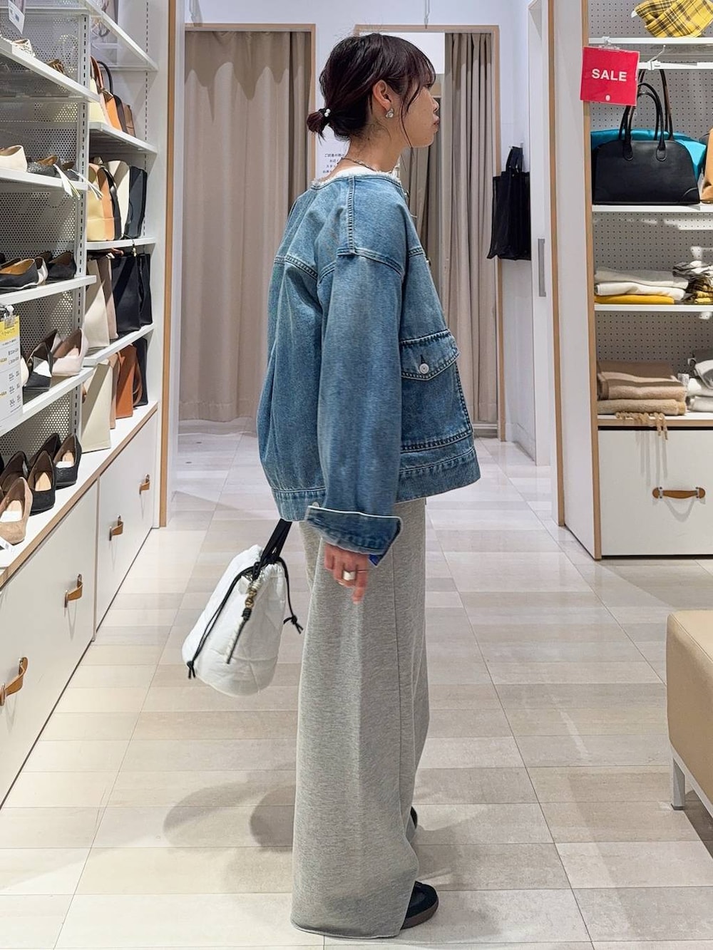 ブラック系のキャミソール、ホワイト系のハンドバッグ、ブルー系のデニムジャケットを着用したレディースの冬コーディネートの3枚目の写真