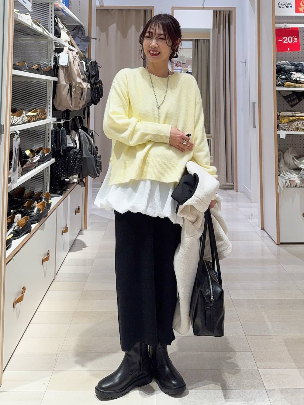 ブラック系のボストンバッグ、ホワイト系のブルゾン、イエロー系のニット/セーターを着用したレディースの冬コーディネートの3枚目の写真