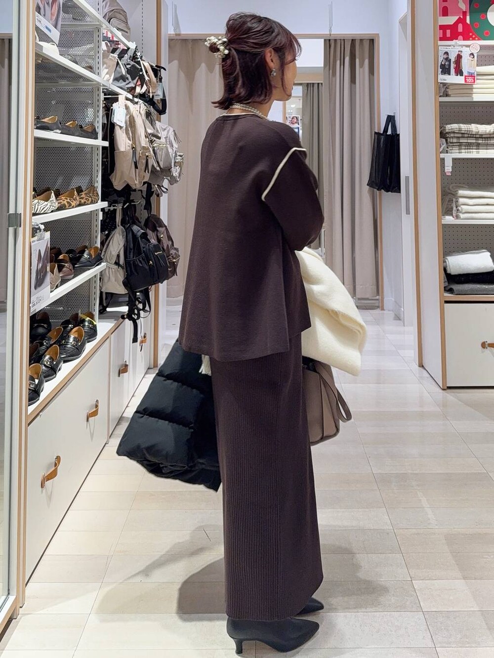 ブラック系のダウンジャケット/コート、ブラウン系のワンピース、ブラック系のブーツを着用したレディースの冬コーディネートの7枚目の写真