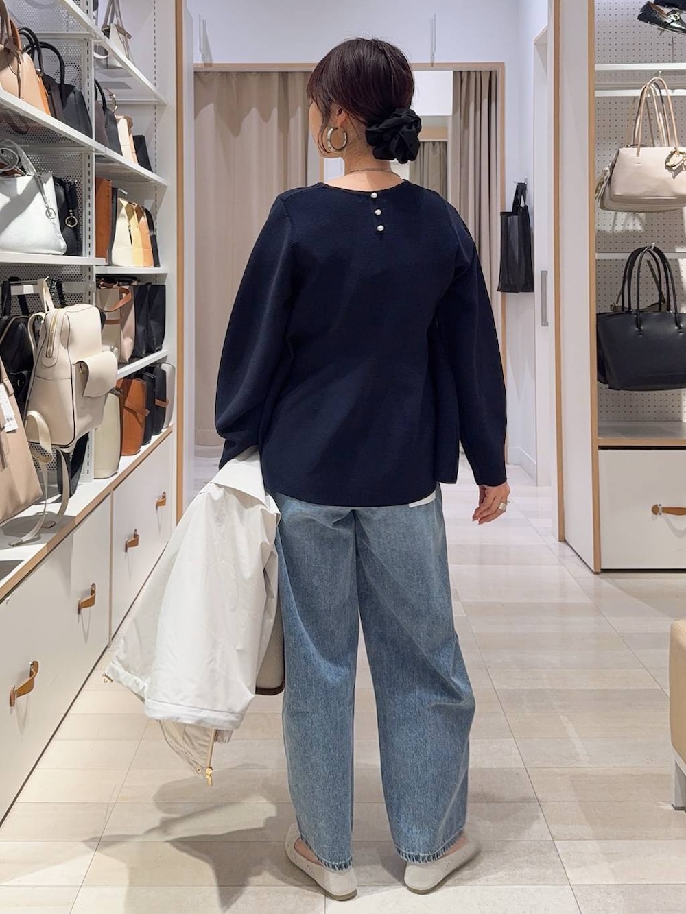 ベージュ系のトートバッグ、ベージュ系のマウンテンパーカー、ブルー系のデニムパンツを着用したレディースの春コーディネートの6枚目の写真