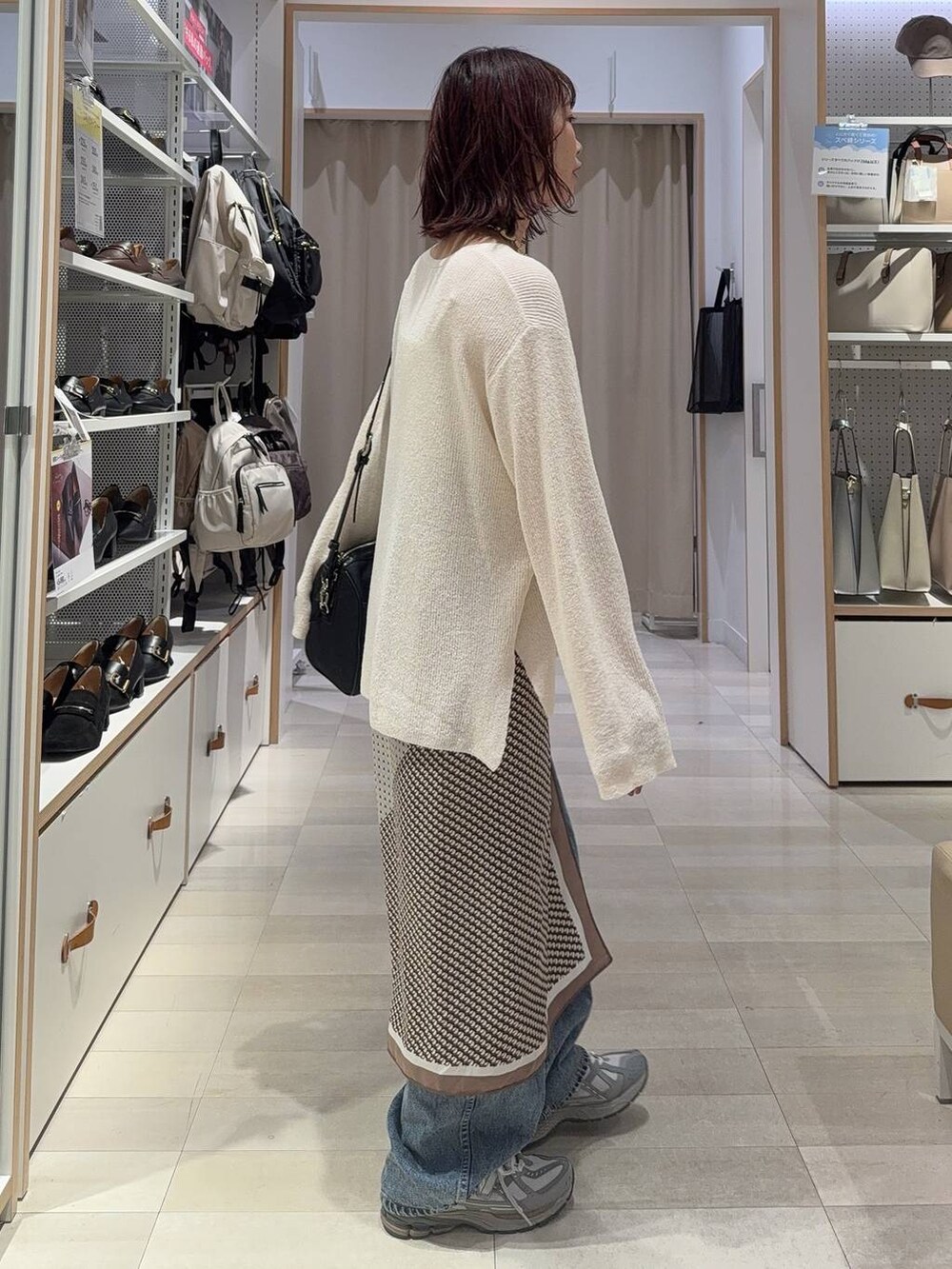 ホワイト系のキャミソール、ブルー系のデニムパンツ、ブラック系のボストンバッグを着用したレディースの秋コーディネートの5枚目の写真