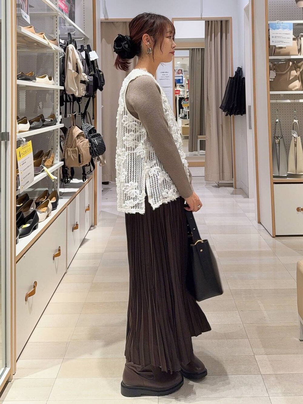 ブラック系のショルダーバッグ、ベージュ系のニット/セーター、ブラウン系のブーツを着用したレディースの秋コーディネートの4枚目の写真