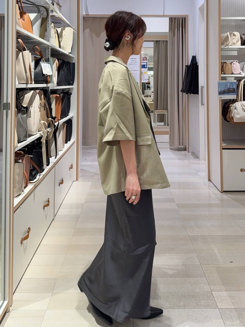 グレー系のスカート、ブラック系のパンプス、その他のネックレスを着用したレディースの春コーディネートの4枚目の写真