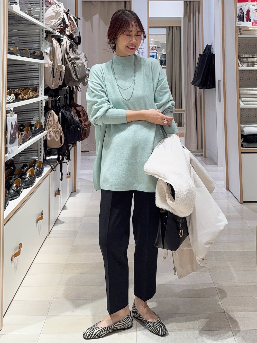 ホワイト系のショルダーバッグ、ブラック系のダウンジャケット/コート、ブラック系のブーツを着用したレディースの冬コーディネートの3枚目の写真