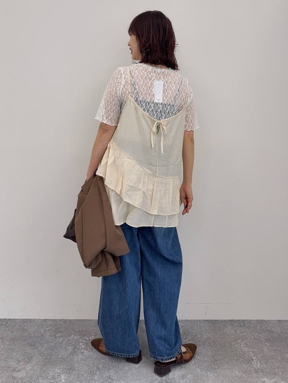 ブルー系のデニムパンツ、ブラウン系のキャミソール、ブラウン系のボストンバッグを着用したレディースの春コーディネートの7枚目の写真