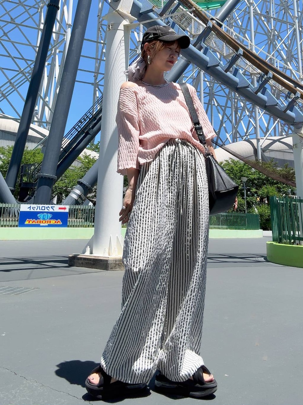 ホワイト系のその他パンツ、シルバー系のネックレス、ブラック系のキャップを着用したレディースの春コーディネートの3枚目の写真
