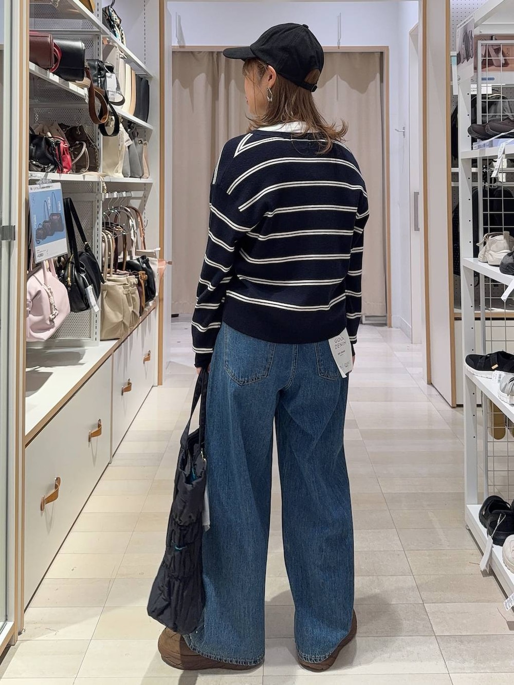 ブルー系のデニムパンツ、ホワイト系のTシャツ/カットソー、ブラック系のトートバッグを着用したレディースの秋コーディネートの3枚目の写真