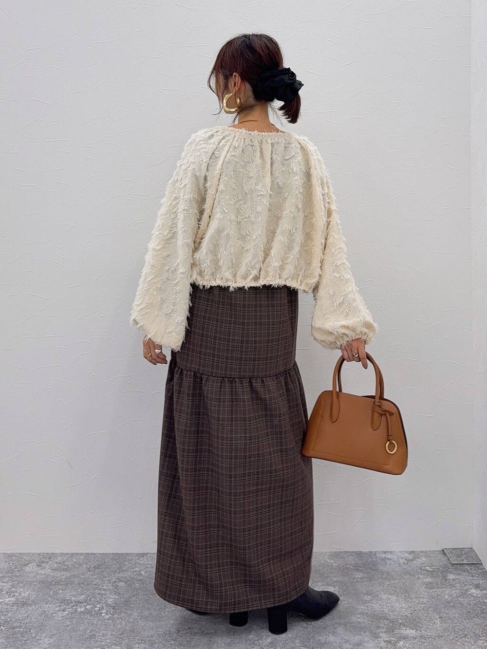 ブラウン系のショルダーバッグ、ブラック系のブーツ、ホワイト系のシャツ/ブラウスを着用したレディースの秋コーディネートの4枚目の写真