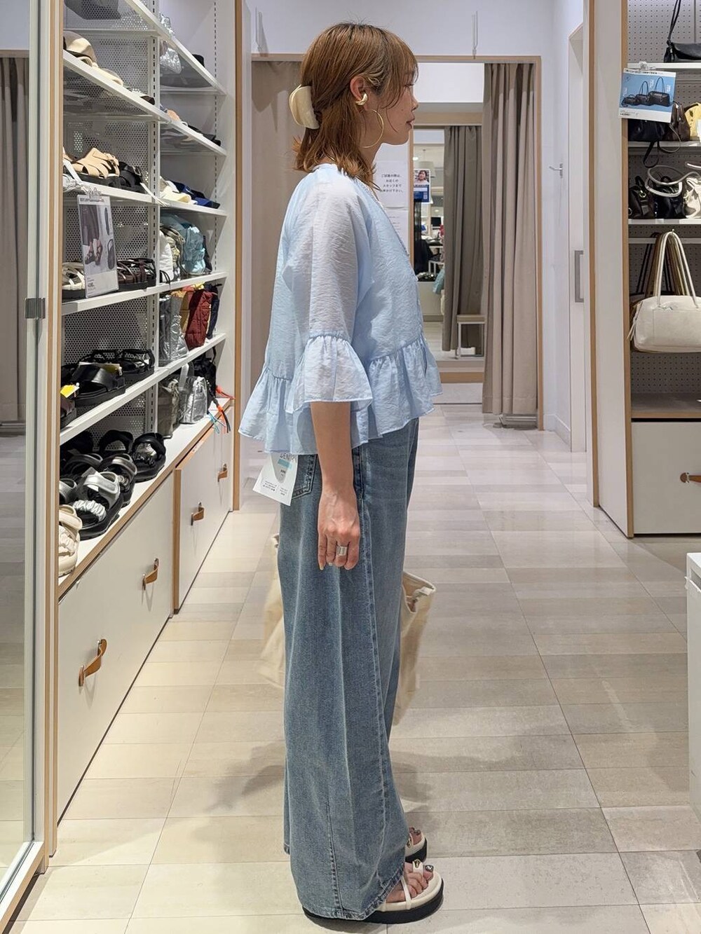 ホワイト系のトートバッグ、ブルー系のデニムパンツ、ホワイト系のサンダルを着用したレディースの春コーディネートの3枚目の写真