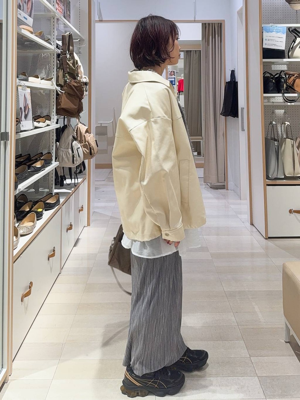 グリーン系のボストンバッグ、ホワイト系のブルゾン、グレー系のスカートを着用したレディースの秋コーディネートの5枚目の写真