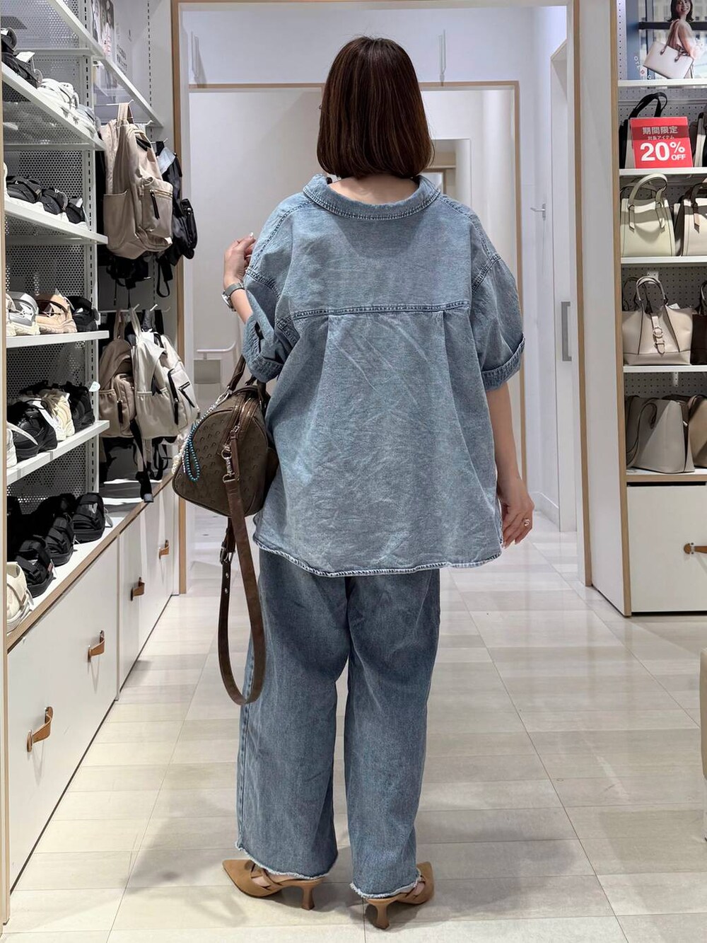 ベージュ系のパンプス、グリーン系のボストンバッグ、ブルー系のデニムパンツを着用したレディースの春コーディネートの4枚目の写真