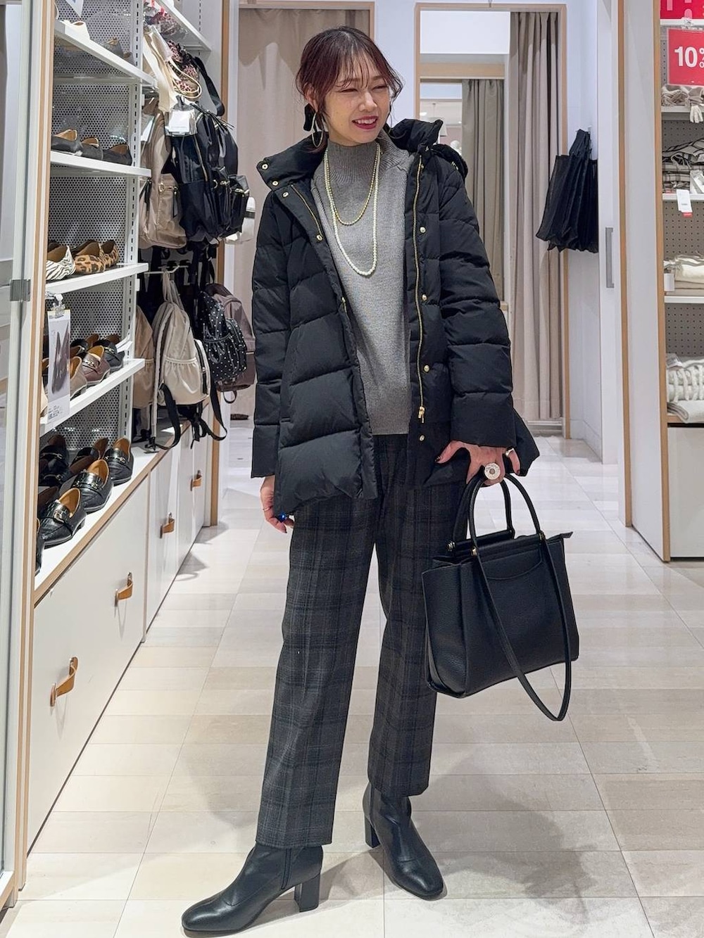 シルバー系のショルダーバッグ、ベージュ系のダウンジャケット/コート、グレー系のニット/セーターを着用したレディースの冬コーディネートの4枚目の写真