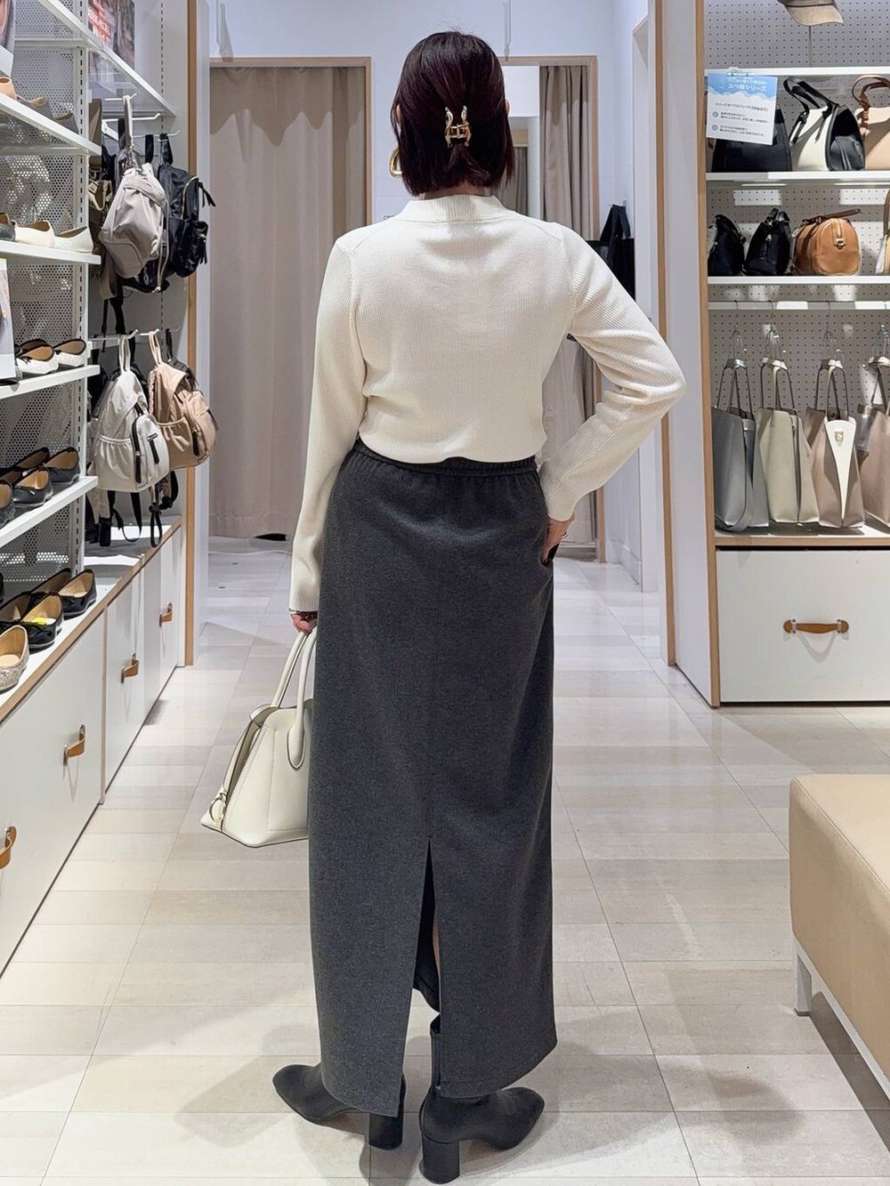 ホワイト系のショルダーバッグ、ブラック系のブーツ、ブラウン系のバレッタ/ヘアクリップを着用したレディースの秋コーディネートの7枚目の写真