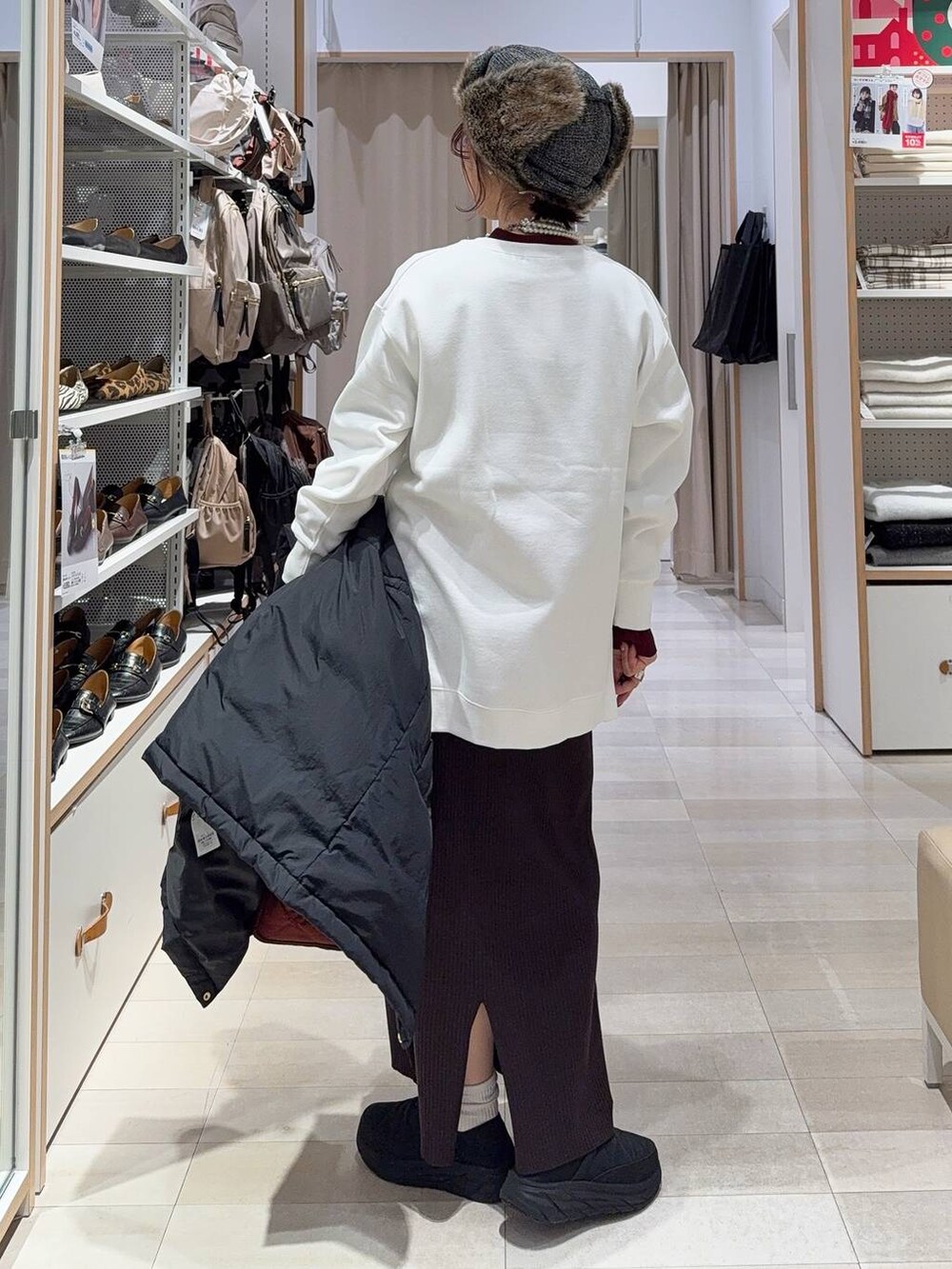 レッド系のトートバッグ、ブラック系のダウンジャケット/コート、レッド系のニット/セーターを着用したレディースの冬コーディネートの9枚目の写真