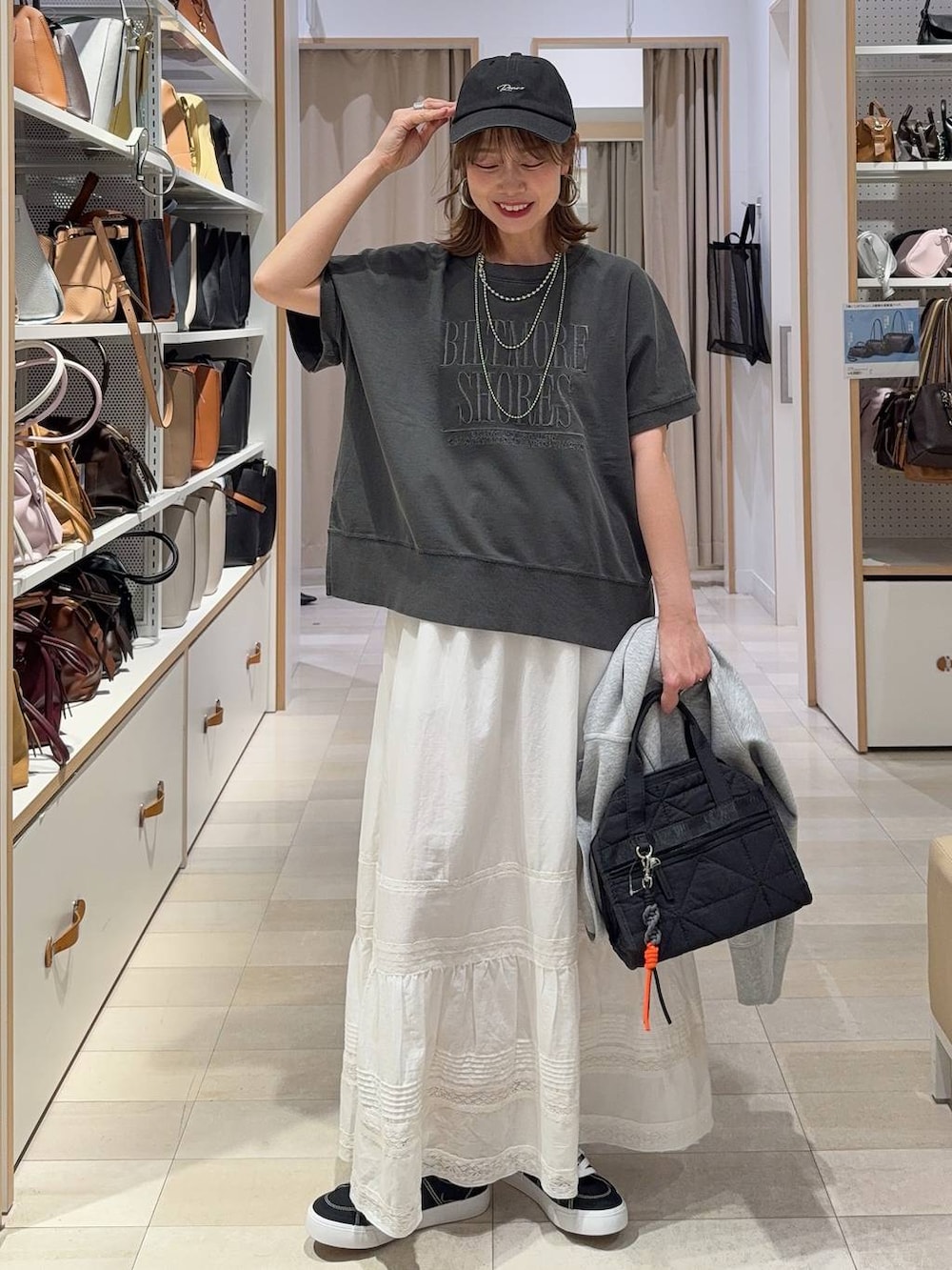 ブラック系のボストンバッグ、グレー系のパーカー、ホワイト系のスカートを着用したレディースの春コーディネートの2枚目の写真