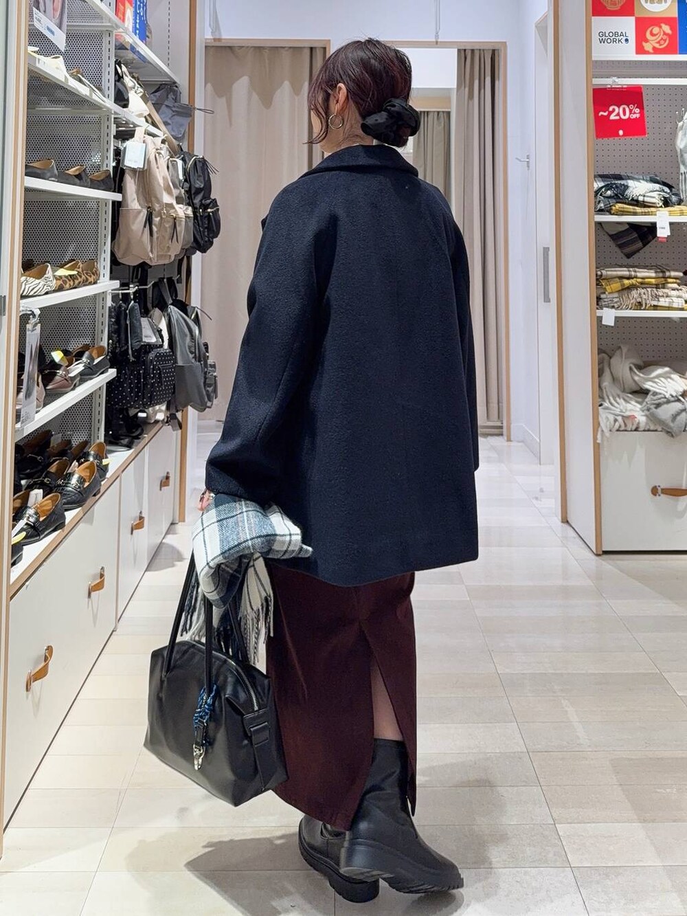 ブラック系のボストンバッグ、ブルー系のチェスターコート、レッド系のスカートを着用したレディースの冬コーディネートの5枚目の写真