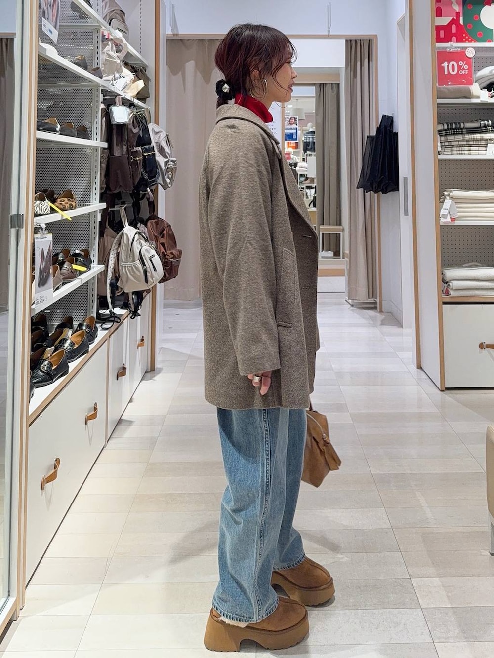 ブラウン系のボストンバッグ、ブルー系のデニムパンツ、ブラウン系のチェスターコートを着用したレディースの冬コーディネートの5枚目の写真