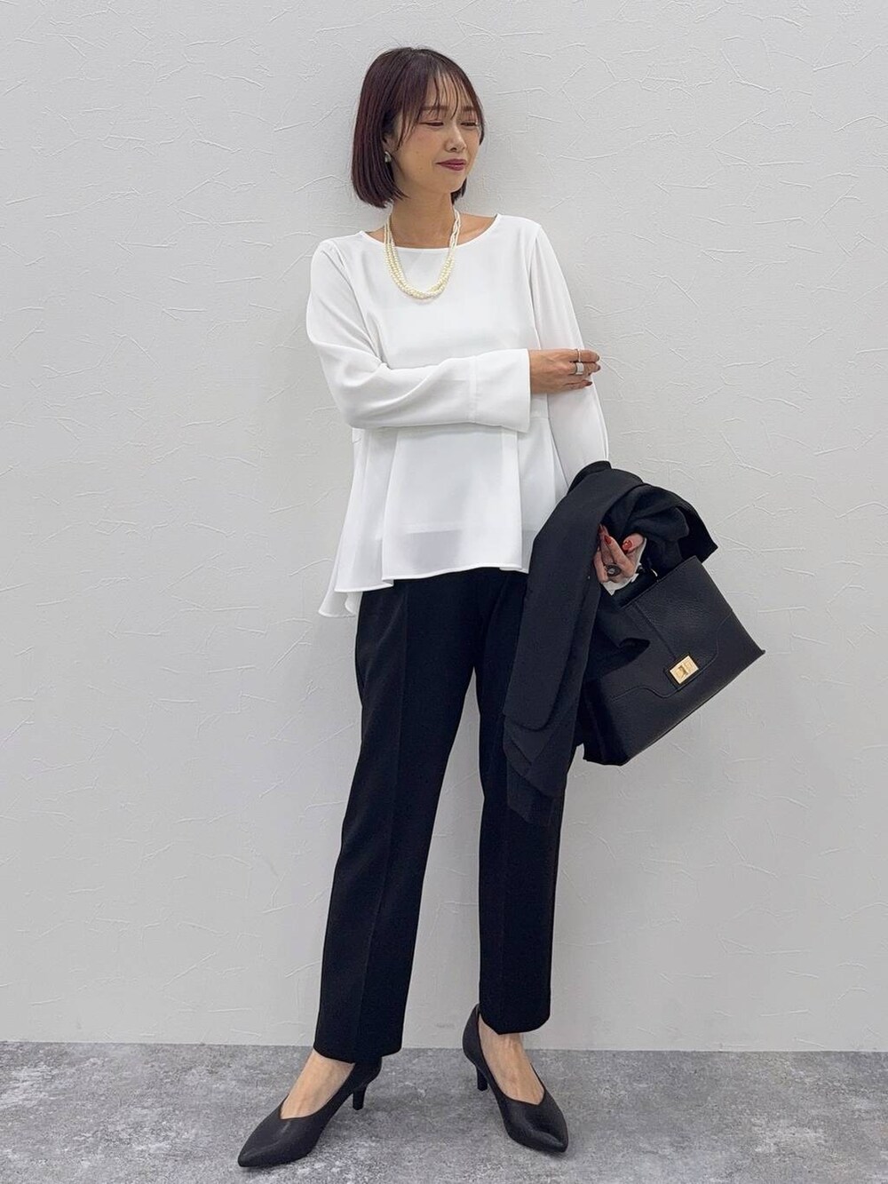 ブラック系のパンプス、ブラック系のセットアップ、その他のネックレスを着用したレディースの秋コーディネートの2枚目の写真