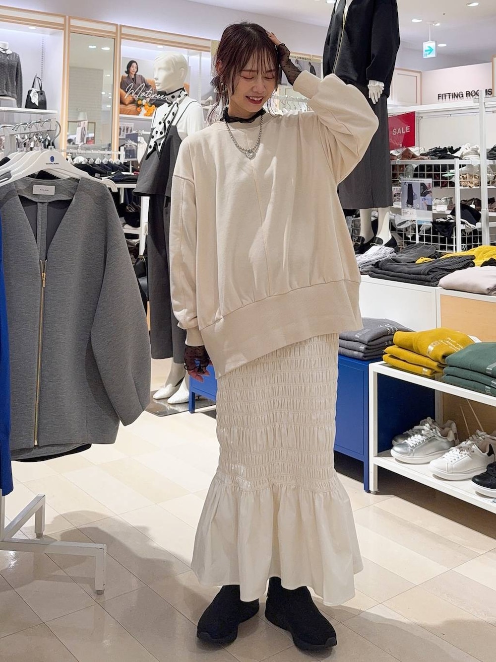 ブラック系のスニーカー、ブラウン系のスカート、ホワイト系のTシャツ/カットソーを着用したレディースの秋コーディネートの3枚目の写真