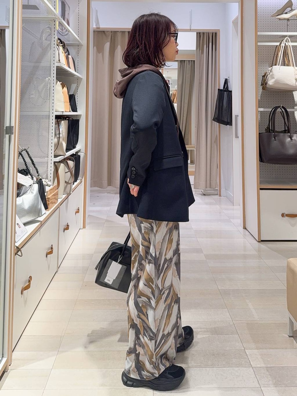 ブラック系のボストンバッグ、ブラック系のスニーカー、ブルー系のテーラードジャケットを着用したレディースの冬コーディネートの6枚目の写真