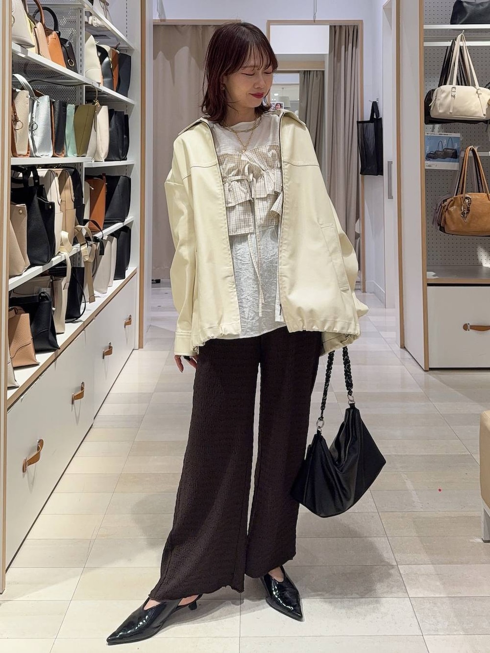 ホワイト系のブルゾン、ブラウン系のキャミソール、ブラウン系のその他パンツを着用したレディースの春コーディネートの3枚目の写真