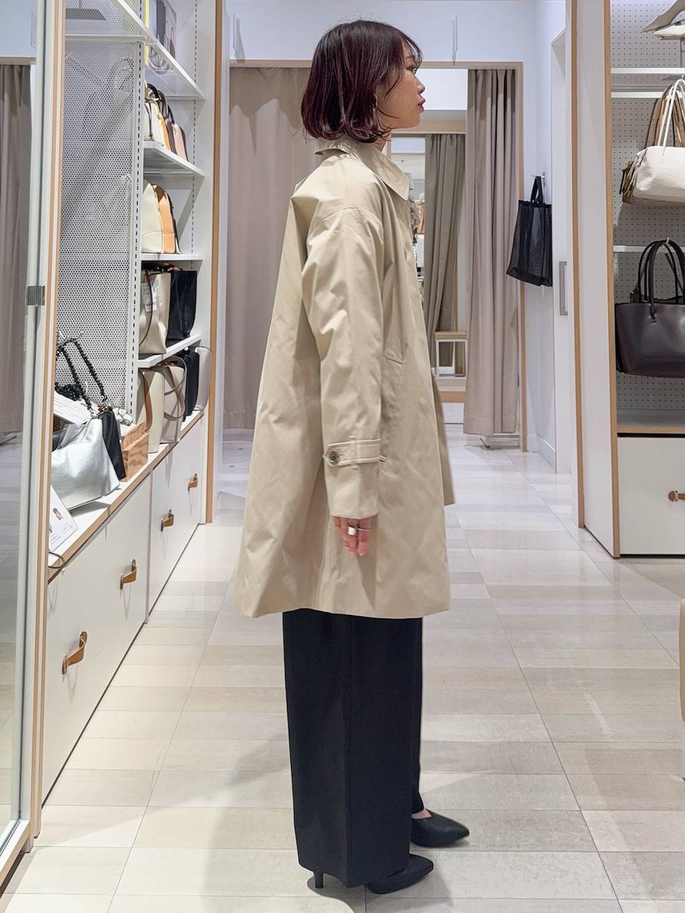 ブラック系のショルダーバッグ、ブラック系のパンプス、ベージュ系のステンカラーコートを着用したレディースの冬コーディネートの3枚目の写真