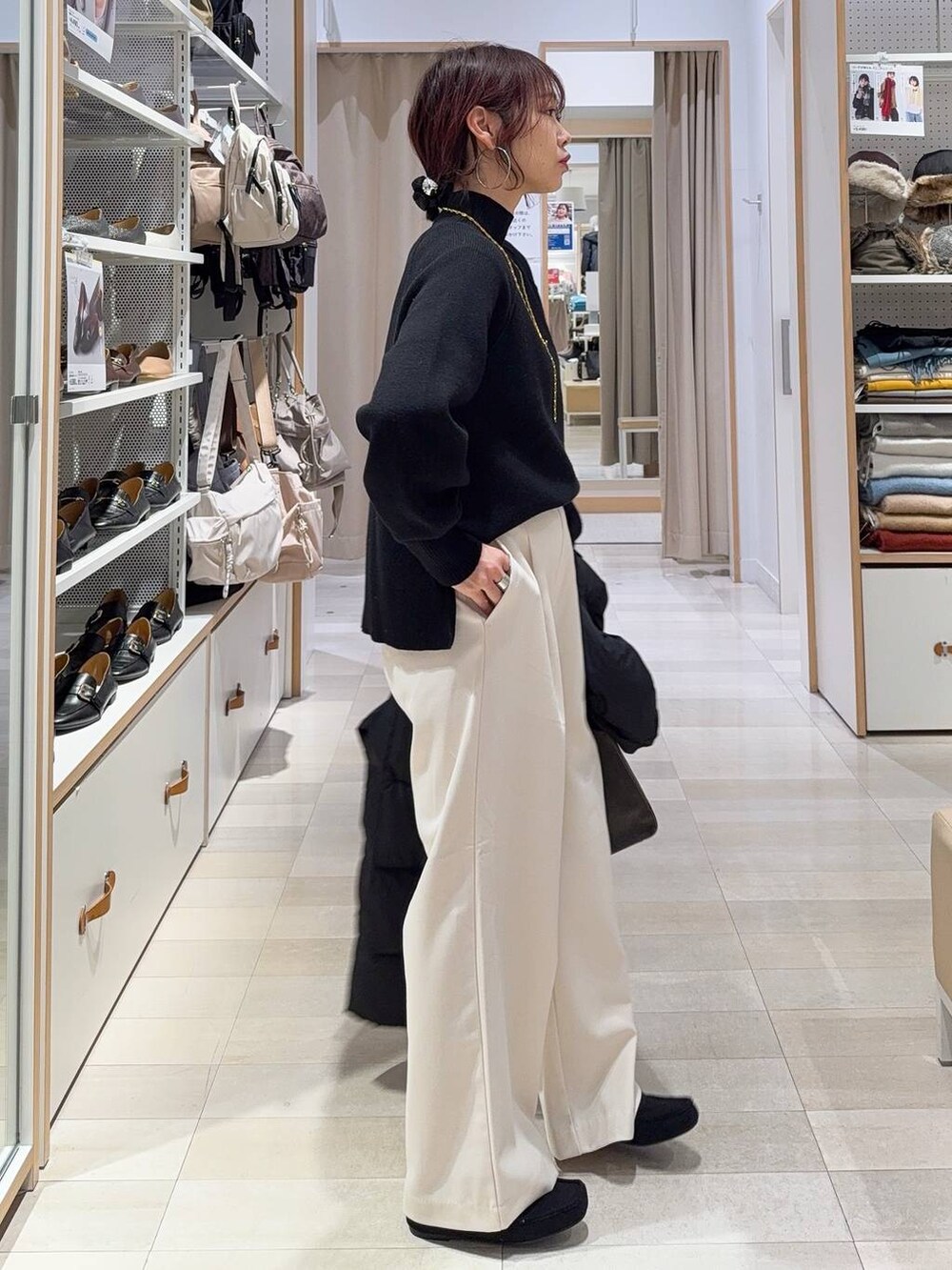 ブラック系のダウンジャケット/コート、グリーン系のショルダーバッグ、ブラック系のニット/セーターを着用したレディースの秋コーディネートの8枚目の写真