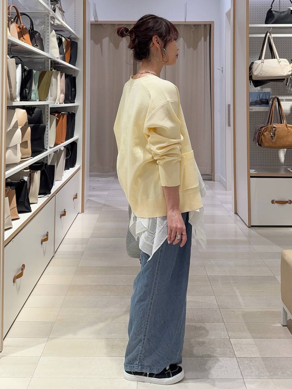 グレー系のブルゾン、イエロー系のカーディガン/ボレロ、ブラック系のスニーカーを着用したレディースの春コーディネートの6枚目の写真