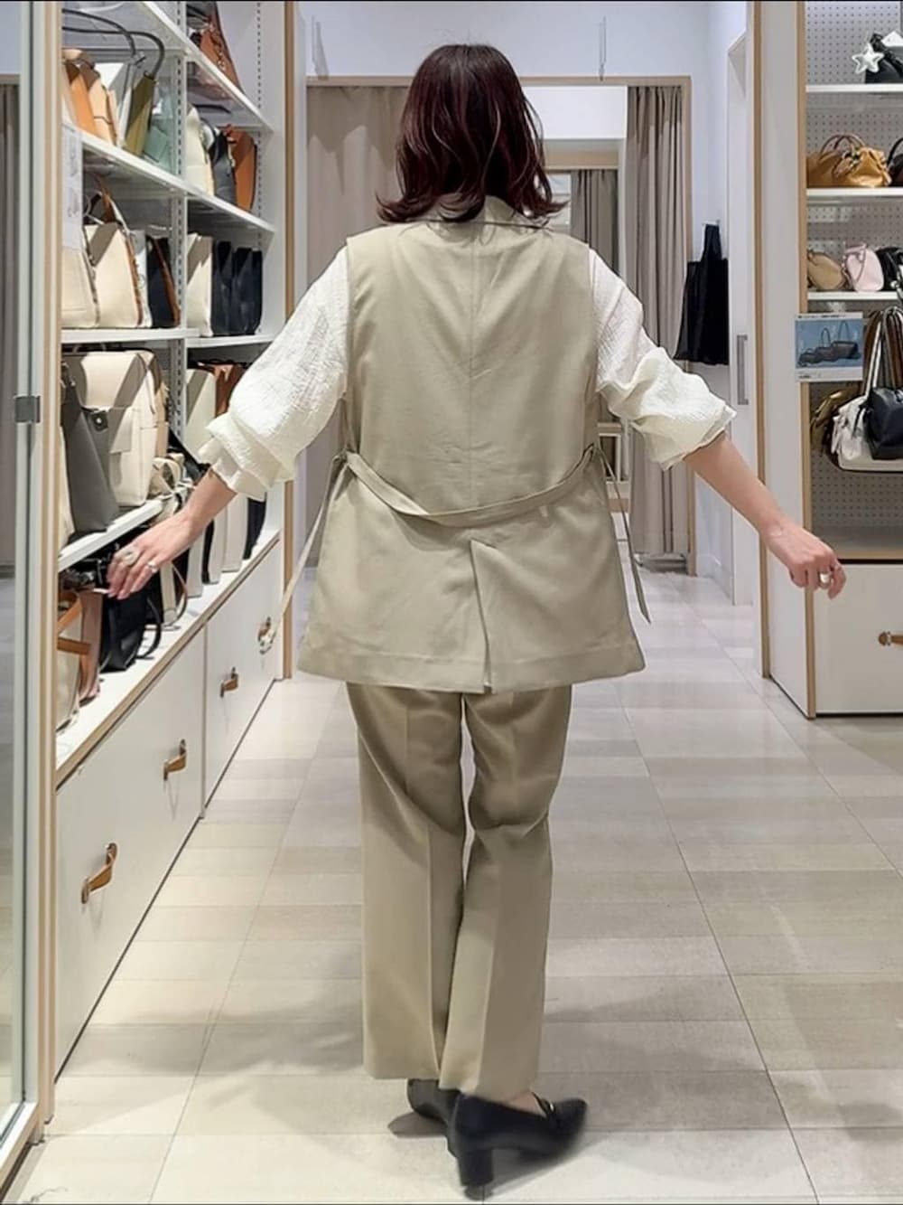 ベージュ系のその他パンツ、ベージュ系のベスト、ブラック系のハンドバッグを着用したレディースの春コーディネートの4枚目の写真