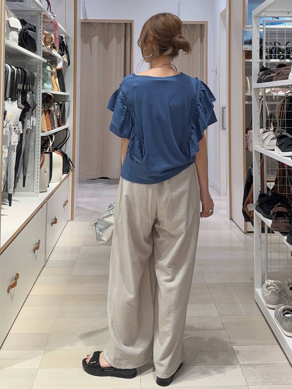 シルバー系のショルダーバッグ、ベージュ系のその他パンツ、ブルー系のTシャツ/カットソーを着用したレディースの夏コーディネートの5枚目の写真