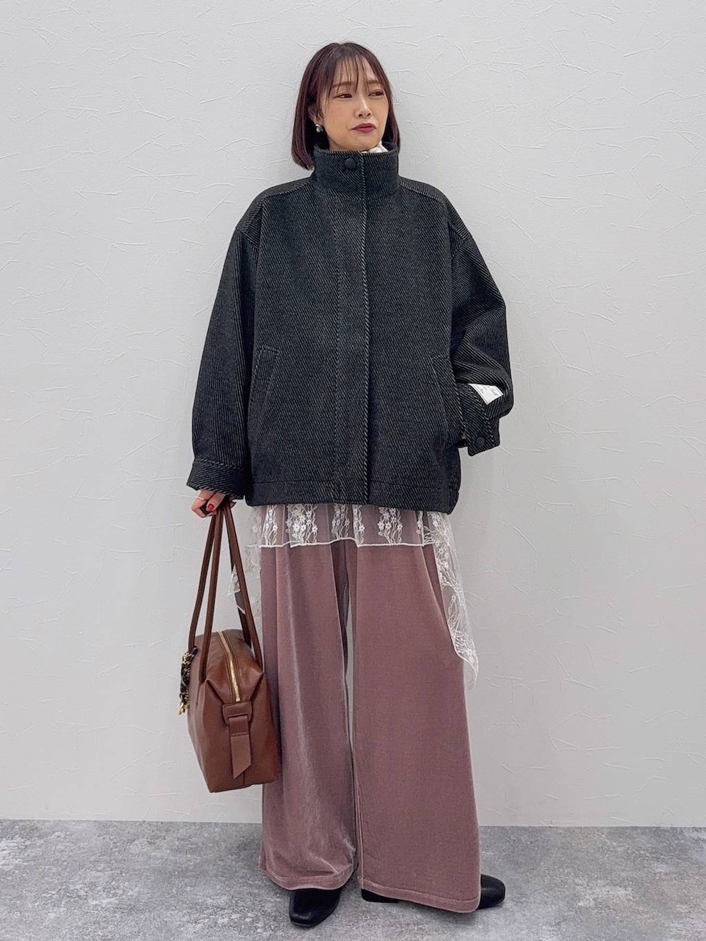 ブラウン系のボストンバッグ、ブラック系のブーツ、ホワイト系のその他トップスを着用したレディースの秋コーディネートの3枚目の写真