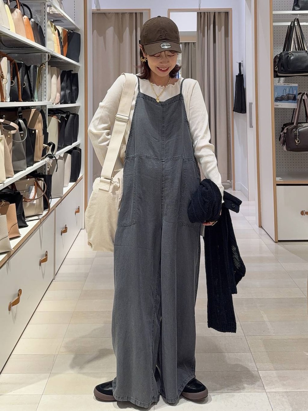 ブラック系のスニーカー、ベージュ系のショルダーバッグ、ホワイト系のTシャツ/カットソーを着用したレディースの春コーディネートの2枚目の写真