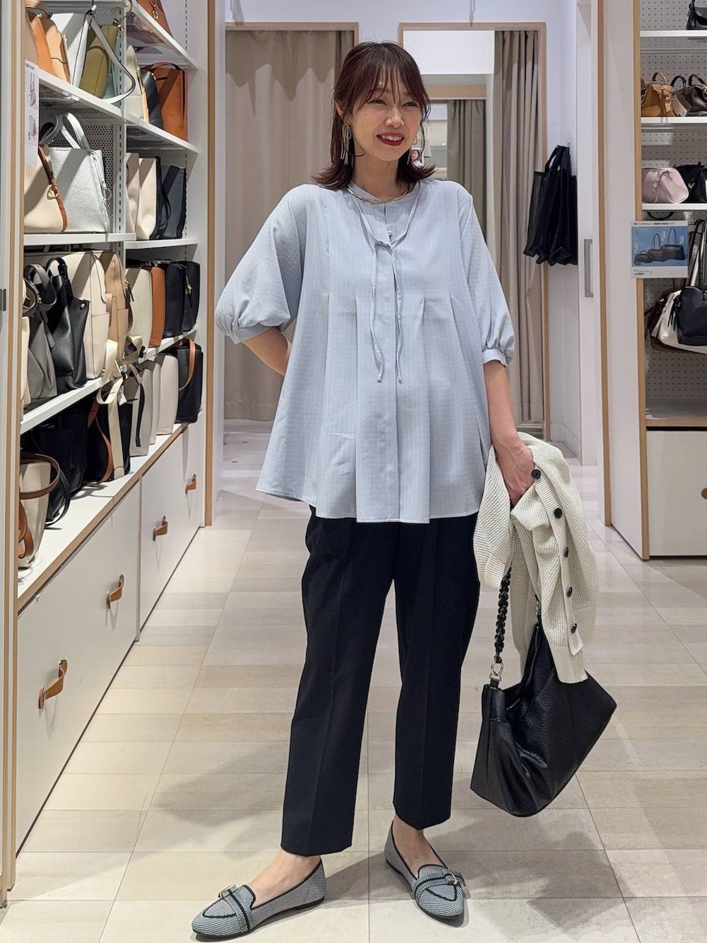 ブラック系のパンプス、ブルー系のスラックス、ホワイト系のカーディガン/ボレロを着用したレディースの春コーディネートの2枚目の写真