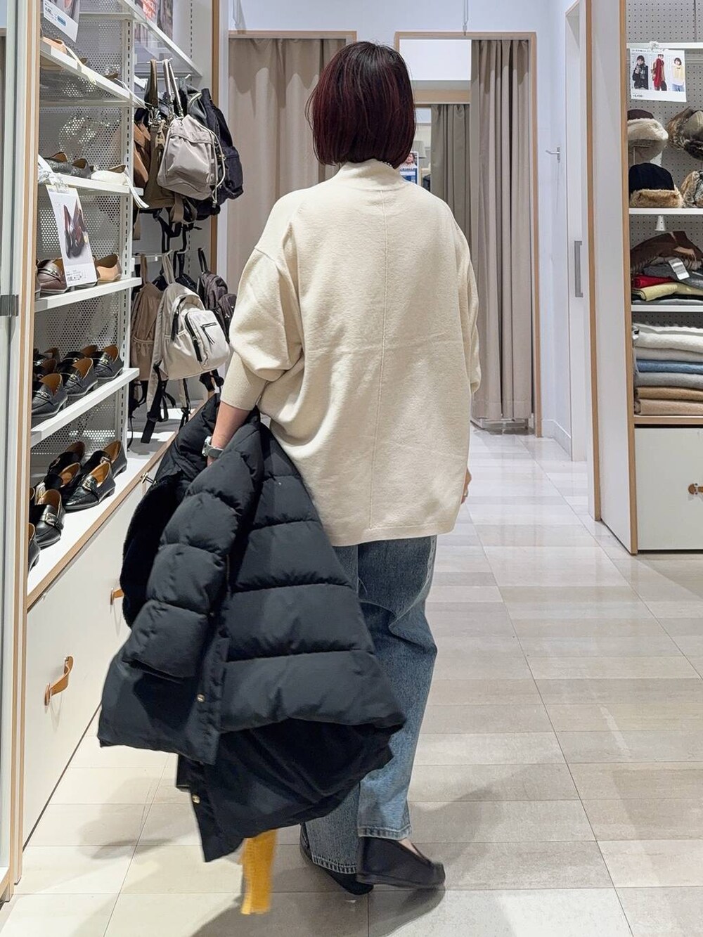 ブラック系のボストンバッグ、ブラック系のダウンジャケット/コート、ブルー系のデニムパンツを着用したレディースの秋コーディネートの8枚目の写真