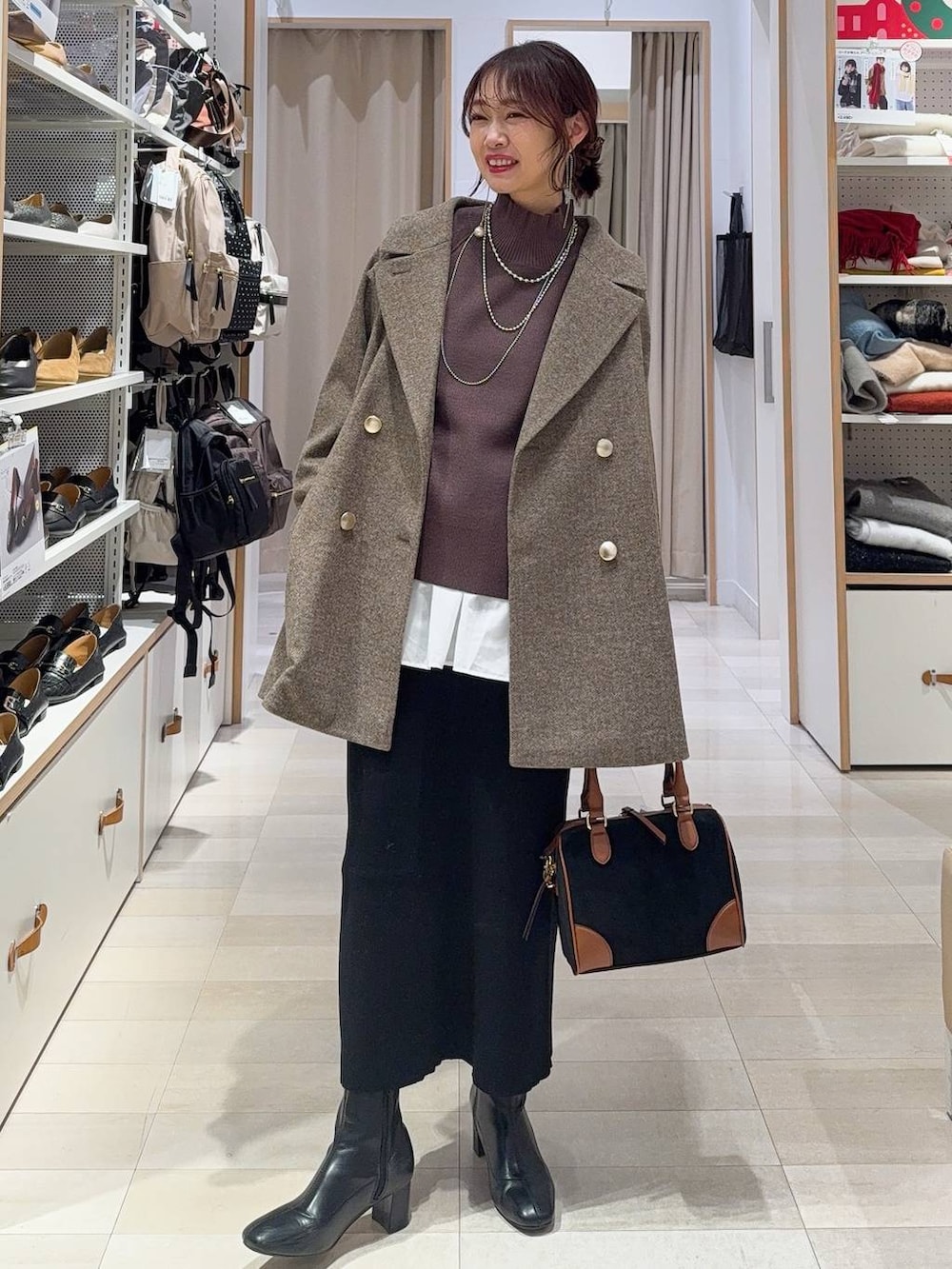 ブラウン系のチェスターコート、ホワイト系のTシャツ/カットソー、ブラウン系のニット/セーターを着用したレディースの冬コーディネートの2枚目の写真