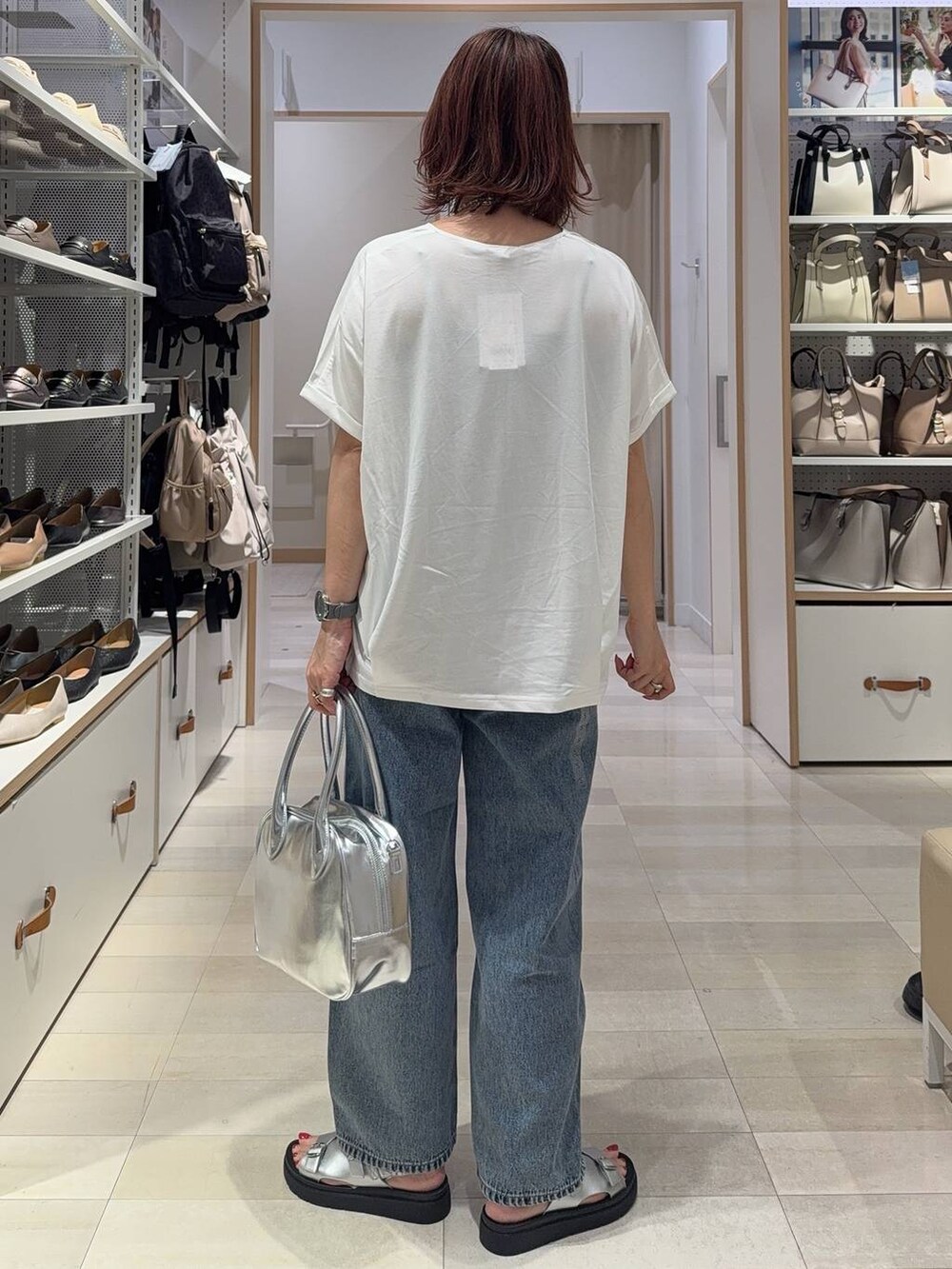 ブルー系のデニムパンツ、グレー系のボストンバッグ、シルバー系のサンダルを着用したレディースの夏コーディネートの4枚目の写真