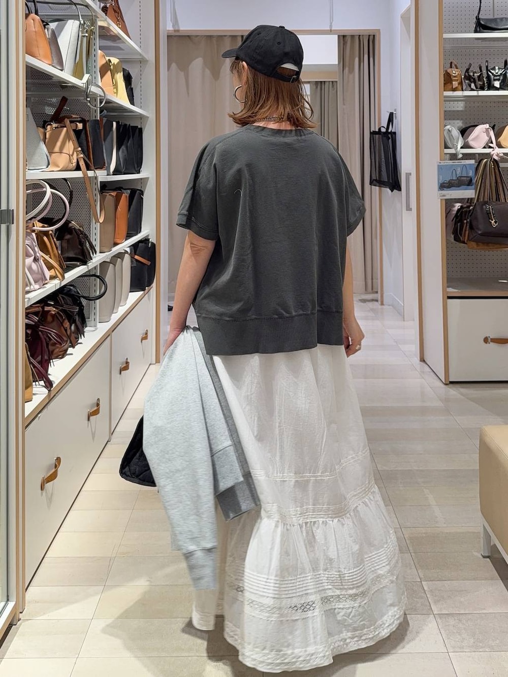 ブラック系のボストンバッグ、グレー系のパーカー、ホワイト系のスカートを着用したレディースの春コーディネートの8枚目の写真