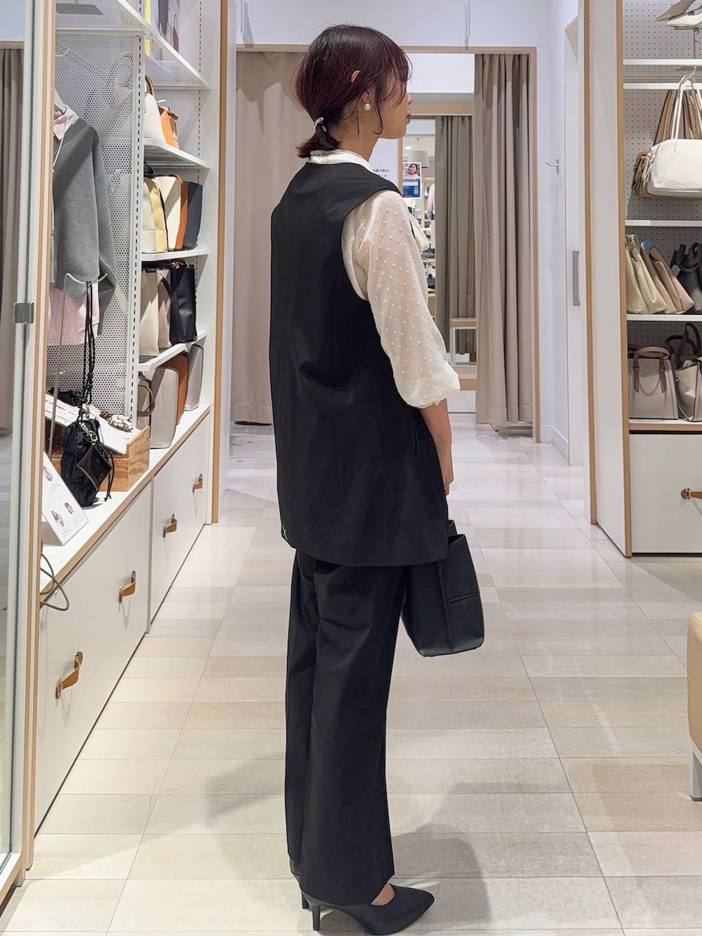 ブラック系のスラックス、ホワイト系のシャツ/ブラウス、ブラック系のその他アウターを着用したレディースの冬コーディネートの5枚目の写真