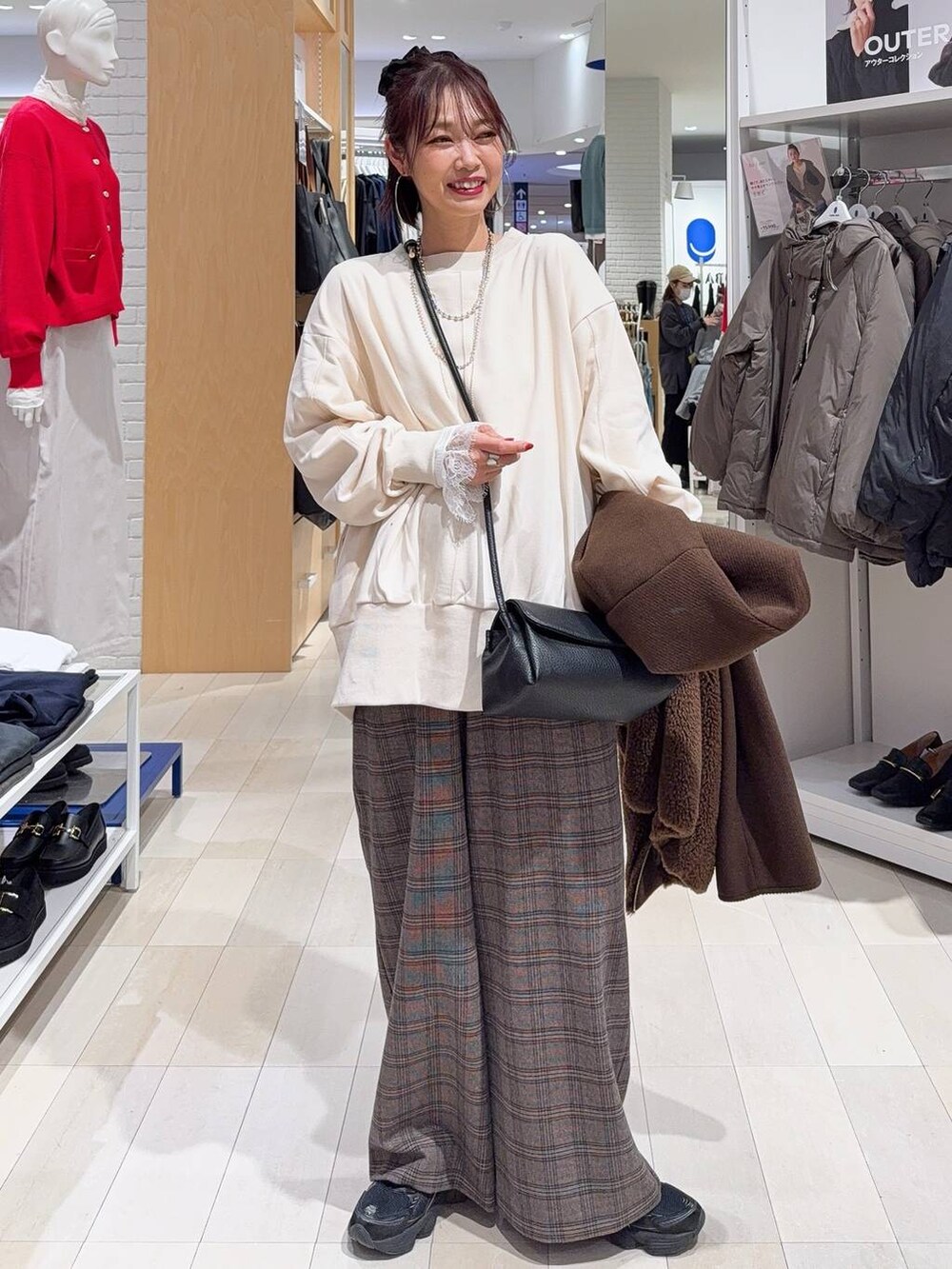 ブラック系のチェスターコート、ブラック系のショルダーバッグ、ホワイト系のTシャツ/カットソーを着用したレディースの秋コーディネートの2枚目の写真