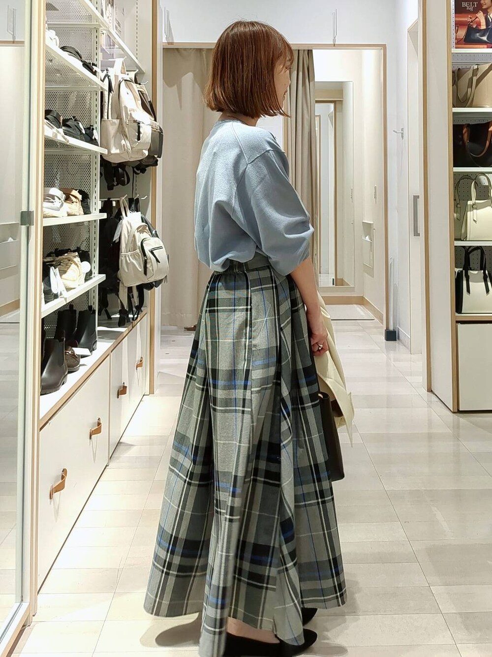 イエロー系のトレンチコート、ブルー系のニット/セーター、ブラック系のショルダーバッグを着用したレディースの春コーディネートの6枚目の写真