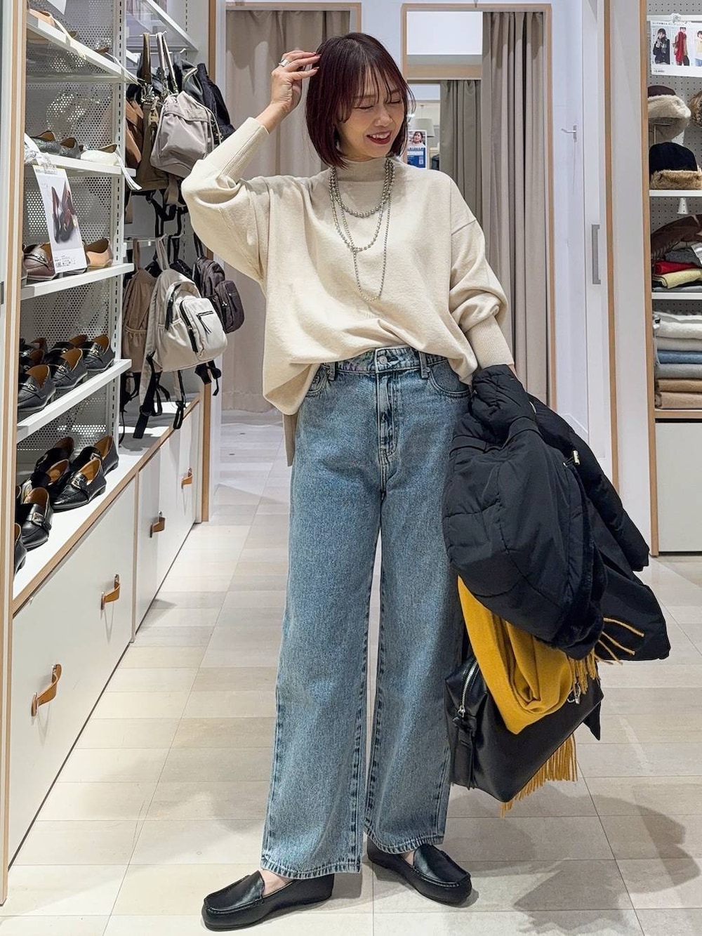 ブラック系のボストンバッグ、ブラック系のダウンジャケット/コート、ブルー系のデニムパンツを着用したレディースの秋コーディネートの2枚目の写真