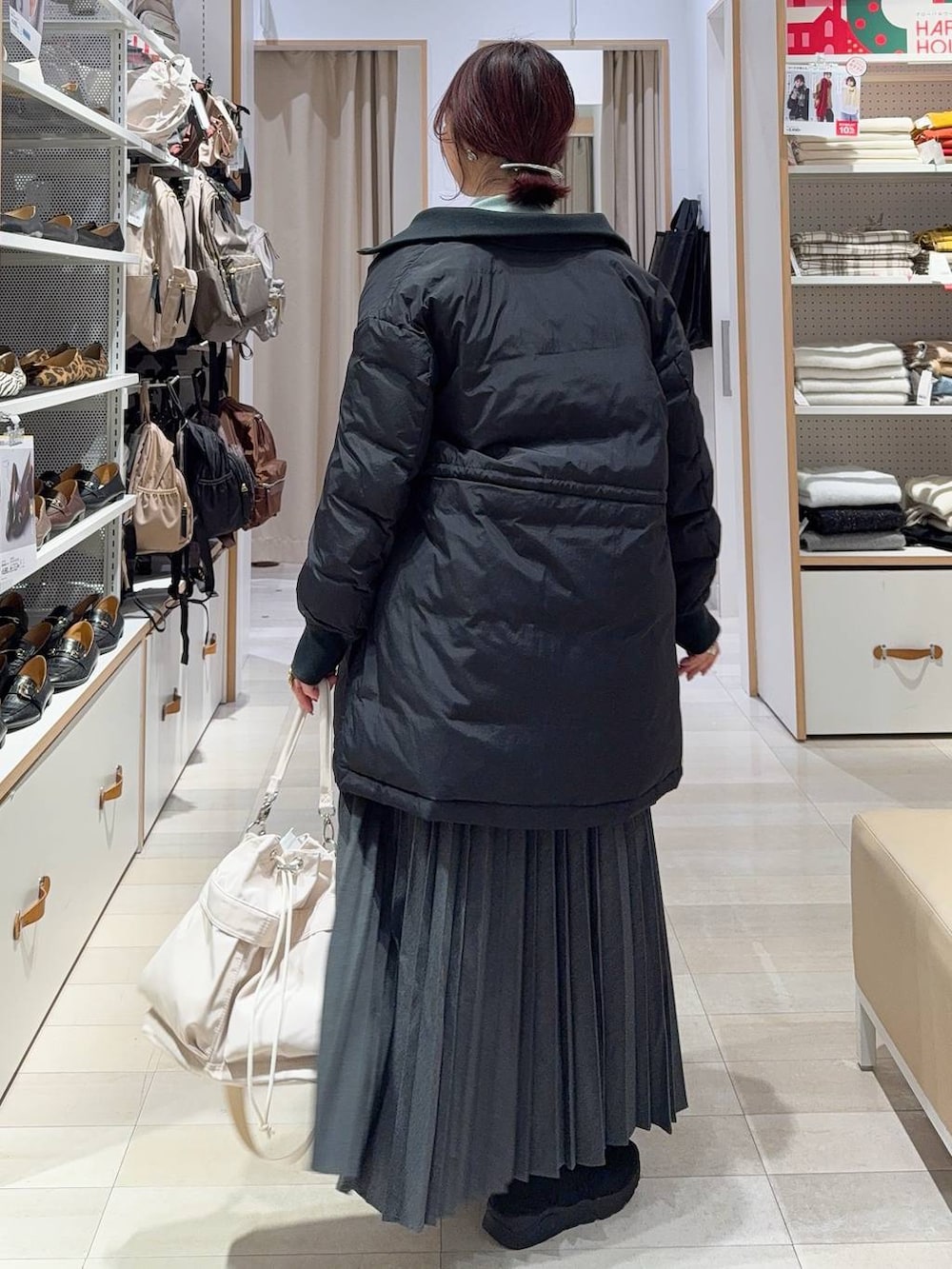 ホワイト系のショルダーバッグ、ブラック系のダウンジャケット/コート、ブラック系のブーツを着用したレディースの冬コーディネートの5枚目の写真