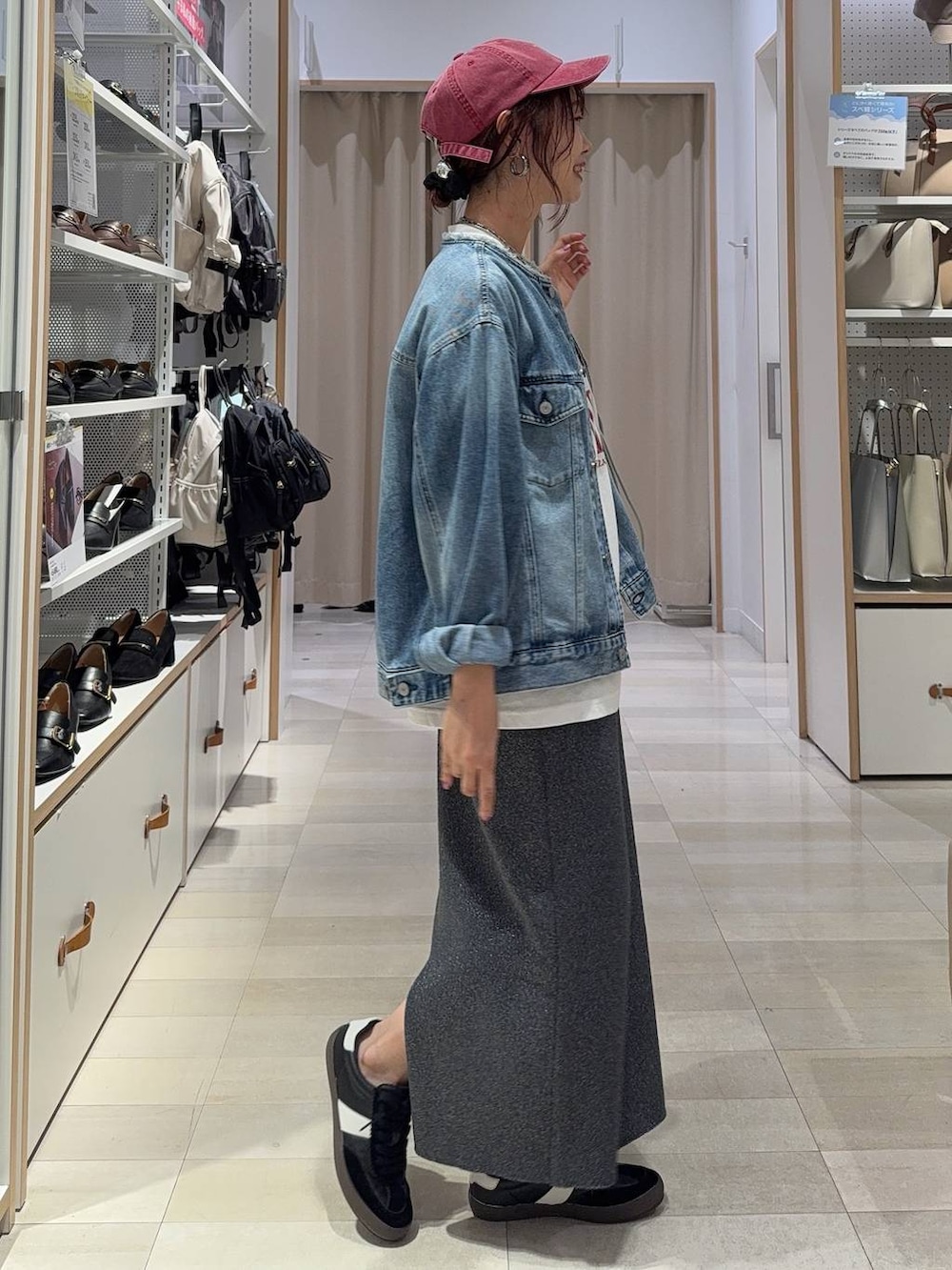 ブラック系のスニーカー、ブルー系のデニムジャケット、シルバー系のハンドバッグを着用したレディースの秋コーディネートの6枚目の写真