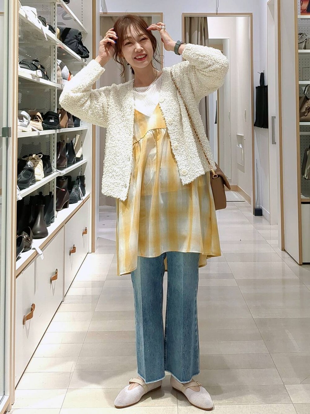 ブルー系のデニムパンツ、ベージュ系のショルダーバッグ、ホワイト系のTシャツ/カットソーを着用したレディースの春コーディネートの2枚目の写真