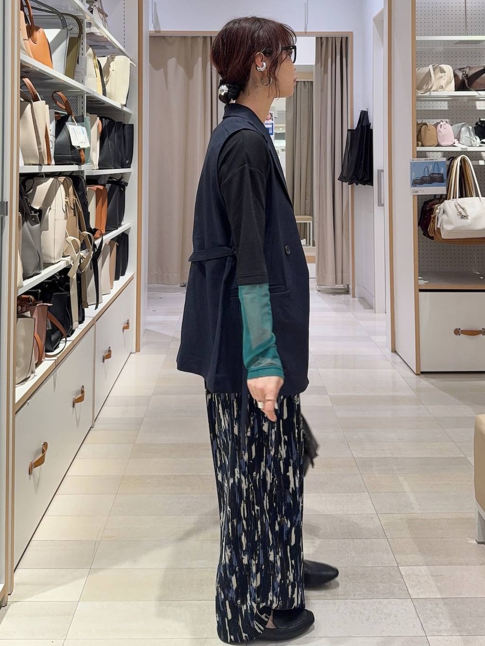 ブラック系のその他シューズ、ブラック系のボストンバッグ、ブルー系のベストを着用したレディースの春コーディネートの4枚目の写真