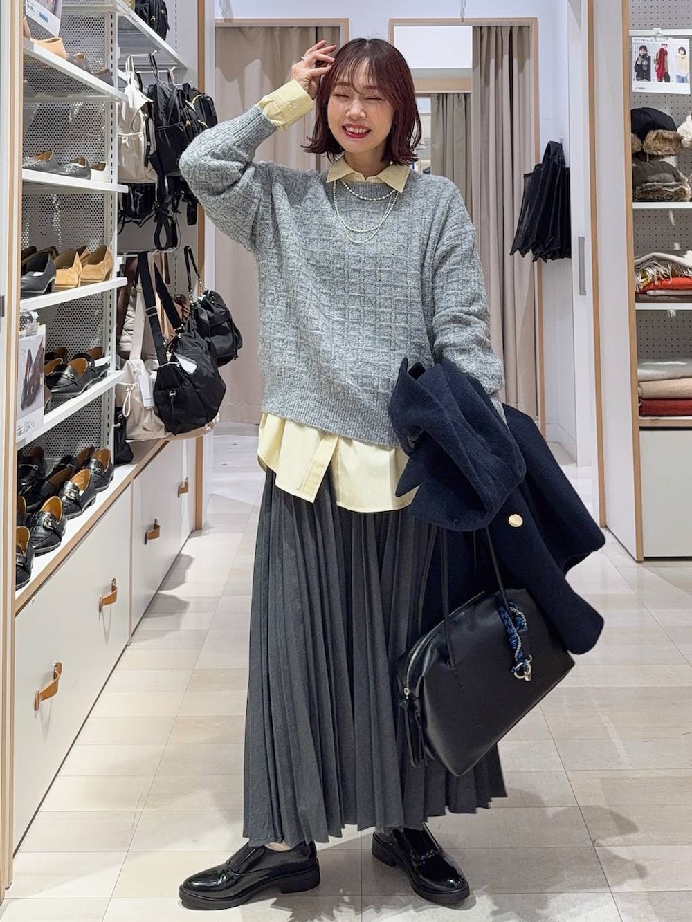 ブラック系のボストンバッグ、ブルー系のチェスターコート、イエロー系のシャツ/ブラウスを着用したレディースの冬コーディネートの3枚目の写真