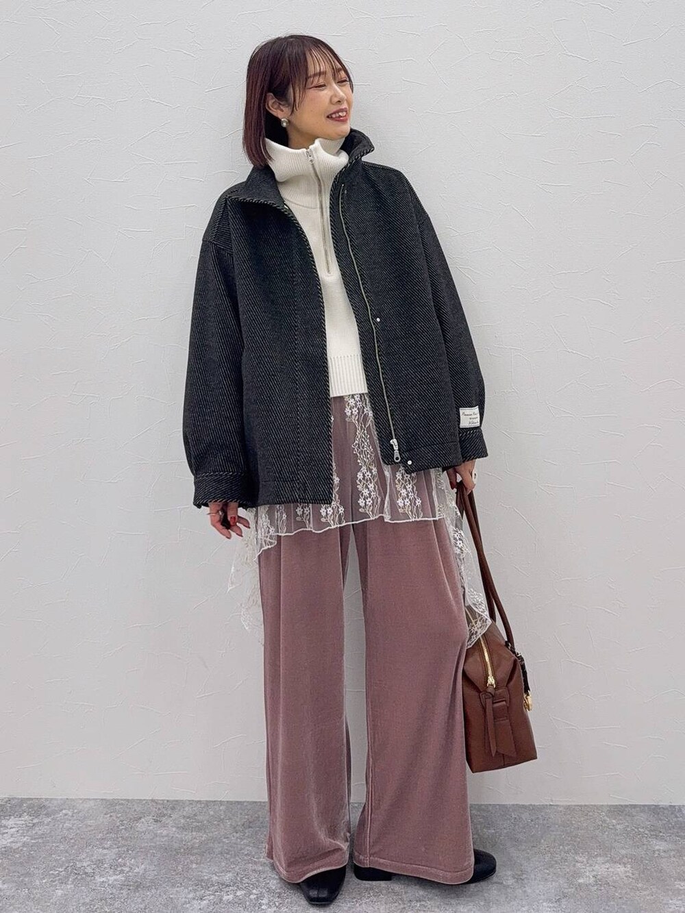 ブラウン系のボストンバッグ、ブラック系のブーツ、ホワイト系のその他トップスを着用したレディースの秋コーディネートの2枚目の写真