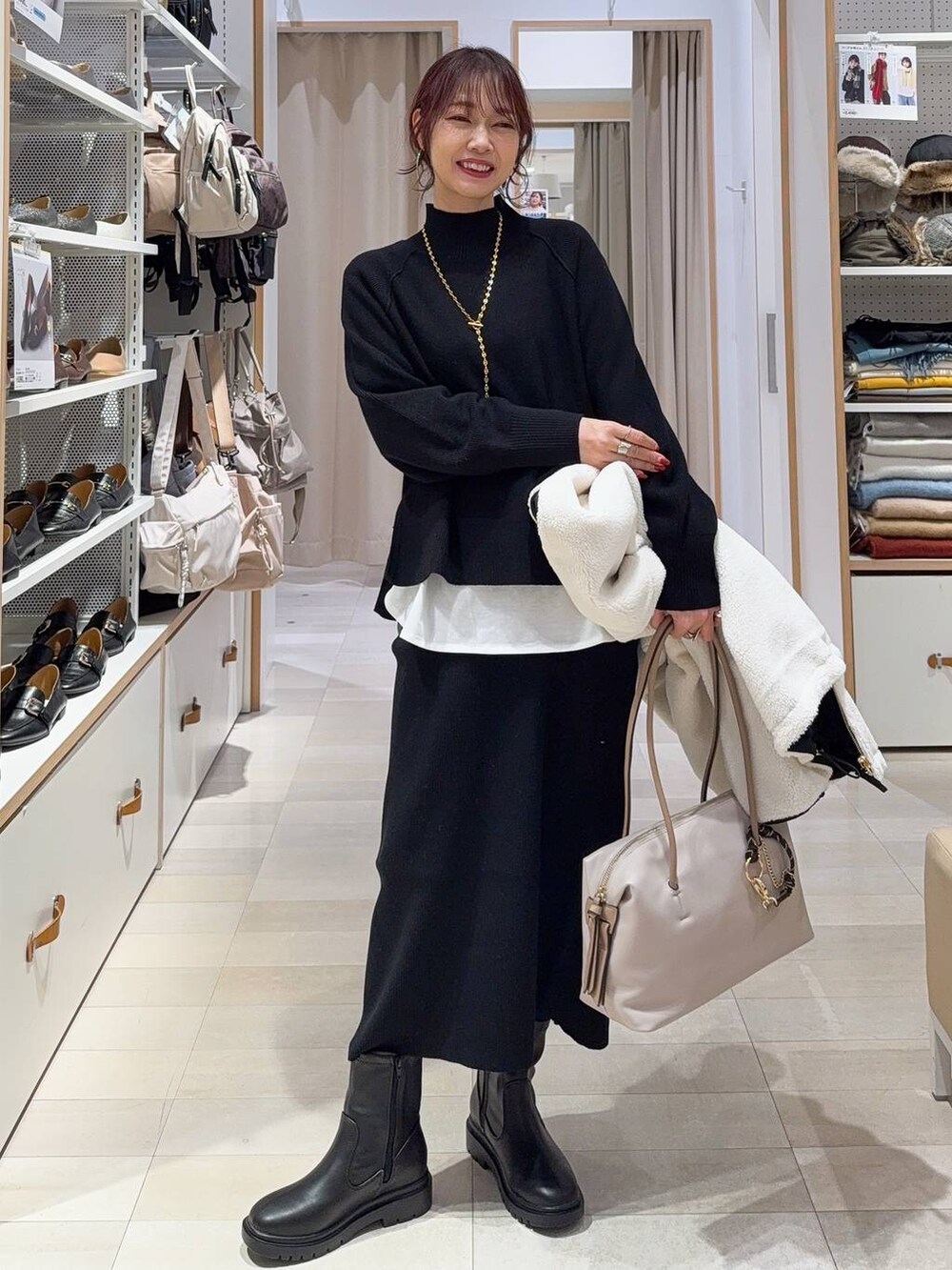 ブラック系のダウンジャケット/コート、グリーン系のショルダーバッグ、ブラック系のニット/セーターを着用したレディースの秋コーディネートの3枚目の写真