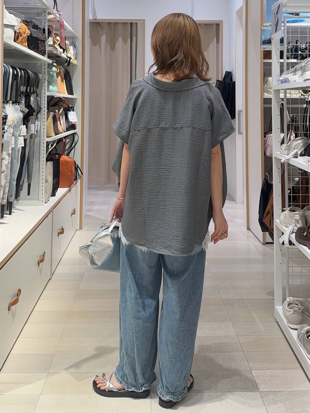 シルバー系のショルダーバッグ、ブルー系のデニムパンツ、ホワイト系のキャミソールを着用したレディースの夏コーディネートの4枚目の写真